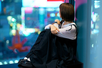 夜の繁華街を見つめる若い女性