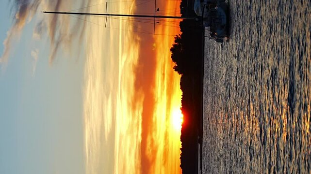 Yachts moored on buoys near the shore in the bay of Uvala Gradina near the town of Vela Luka on the island of Korcula at sunset lights in Croatia. Vertical video