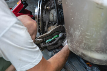 Mechanic man installing new brake disc and brake pads on car, car repair