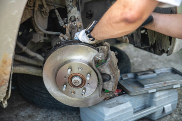 Mechanic man installing new brake disc and brake pads on car, car repair
