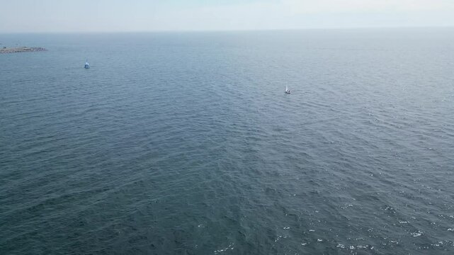 Drone flying towards a small sail boat on Lake Ontario on a sunny day