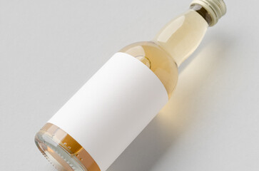 Miniature spirits, liquor bottle mockup. Clear glass, amber liquid with a blank label.