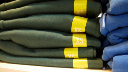 Close-up of many folded clothes sorted by size and color in a clothing store