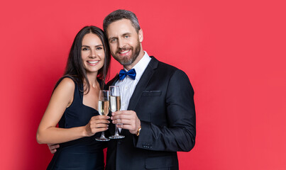 Couple at formal occasion. Romantic date celebrations. Valentines day. Celebrate anniversary. Couple in love celebrate engagement. Elegant couple drink champagne isolated on red. Cheering couple
