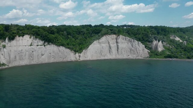 Drone aerial view of Scarborough Bluffs on a sunny day with clouds. Cliffs, bluffs with lake, lush tree canopies