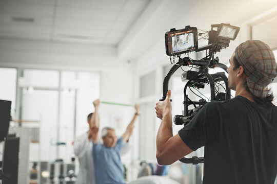 Man, videographer and recording with camera for online vlog, filmmaking or documentary at studio. Young male person or producer with physical therapist for behind the scenes, production or practice