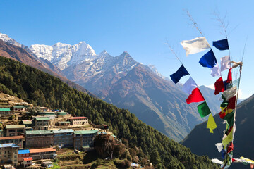 View onto a neighborhood of Namche Bazaar, Bazar with colorful prayer flags next to it and Mount...