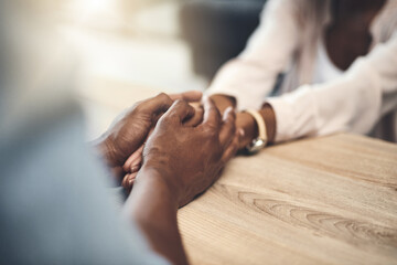 Obraz premium Marriage, trust and couple with holding hands on table for partnership, compassion and appreciation. Care, support and people with connection in love commitment for empathy, forgiveness and kindness