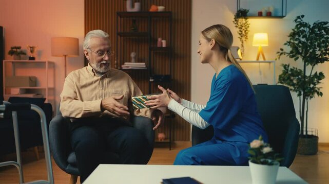 Professional nurse giving birthday gift to senior man from charitable foundation