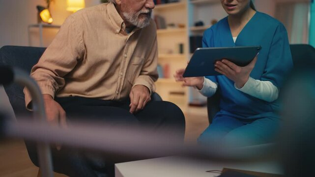 Caring nurse helping elderly man to create account on social media using tablet