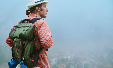 Man with backpack exploring foggy mountain landscape, embracing adventure in nature