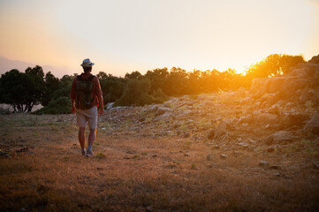 Backpacker exploring nature at sunset with hiking gear in mountain landscape