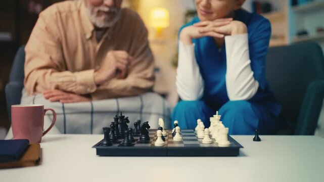Medical worker playing chess with elderly man in retirement home, brain exercise