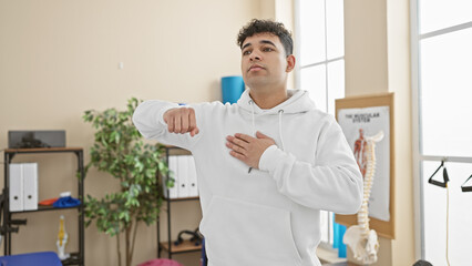 Handsome man stretching in sunny physiotherapy clinic room, conveying wellness and rehab.