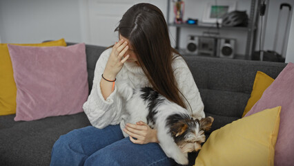 A young hispanic woman relaxes with her biewer terrier in a cozy living room, evoking comfort and companionship.