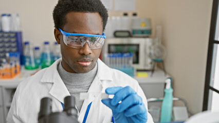 African american male scientist analyzing a specimen in a laboratory setting, portraying research...