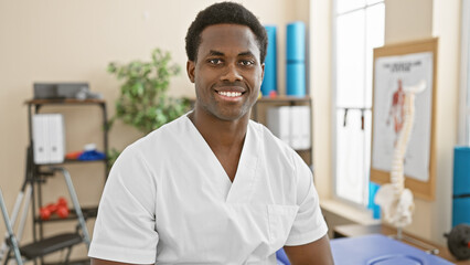 Portrait of a smiling african man in white medical uniform at a clinic, conveying a professional healthcare environment.