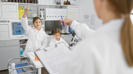 Young hispanic woman teaching girls in a science laboratory classroom, providing education and learning opportunities.