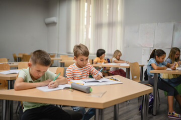 Young students do tasks and write on notebook on the class