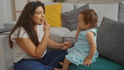 Woman and toddler girl in a living room interacting together, conveying love, family, and indoor...