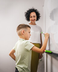 The boy write answer at the maths lesson on the board in the classroom