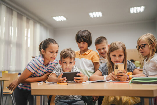 Young students use cellphone for video games on a break at school
