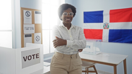African american woman with curly hair and glasses, standing with arms crossed in an electoral...