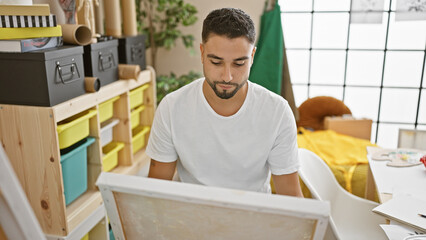 Fototapeta premium Young adult man with beard focusing on creative work in a bright art studio interior