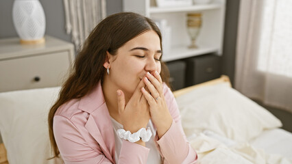 Young hispanic woman smiling with closed eyes in a cozy bedroom setting, exuding a relaxed and comfortable atmosphere.