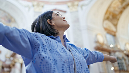 Young beautiful hispanic woman visiting church with open arms at St. Karl BorromÃ¤us church