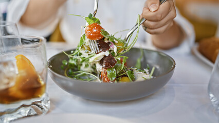 Young woman mixing burrata salad at the restaurant