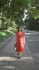 Heartwarming sight - cheerful beautiful hispanic woman wearing glasses enjoying leisurely summer walk, radiating happiness while smiling at meiji temple, tokyo's green park