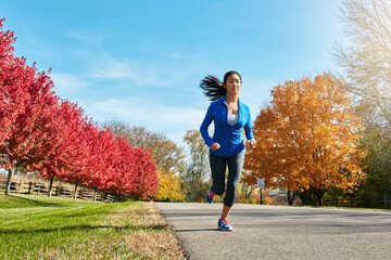 Fototapeta premium Asian woman, running and fitness with exercise in nature for cardio workout or outdoor training in countryside. Active female person, athlete or runner for race, sprint or health and wellness on road