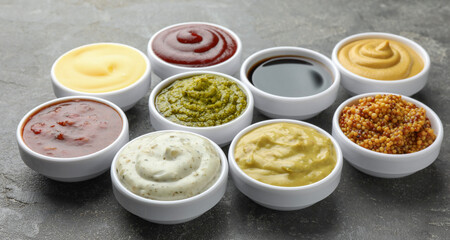 Many different sauces in bowls on grey table