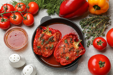 Tasty stuffed peppers in dish and ingredients on light grey table, flat lay