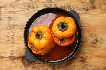 Tasty stuffed peppers in pan on wooden table, top view