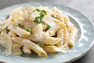 Delicious pasta with green peas, cheese and creamy sauce on table, closeup