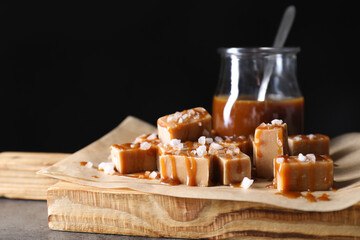 Tasty candies, caramel sauce and salt on grey table, closeup