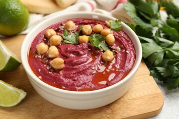 Tasty beet hummus with chickpeas and parsley in bowl on light table, closeup