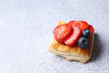 Tasty puff pastry with berries on light grey table, space for text