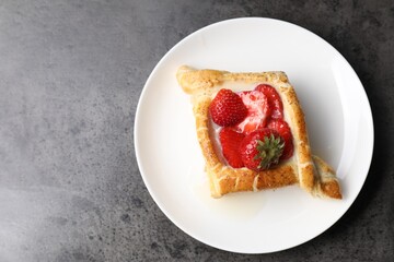 Tasty puff pastry with strawberries on grey table, top view. Space for text