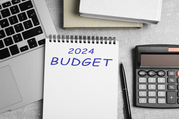 Notebook with word 2024 Budget, calculator and laptop on light table, flat lay