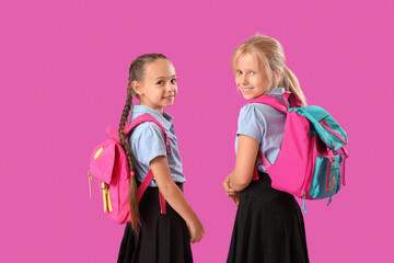 Little classmates in stylish uniform with backpacks on purple background