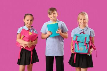 Little classmates in stylish uniform with notebooks and backpacks on purple background