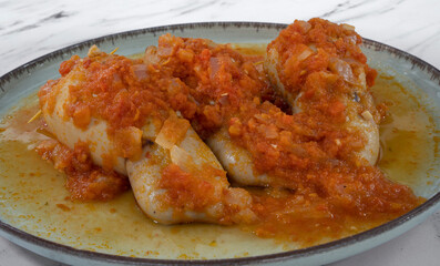 Seafood. Closeup view of stuffed squids with tomato sauce on the white marble table.	
