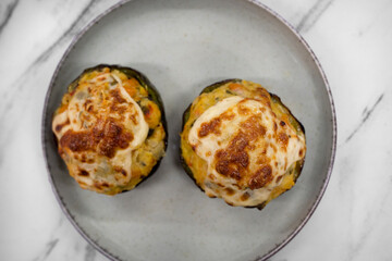 Top view of stuffed zucchinis with crispy cheese in a dish on the white marble table. 