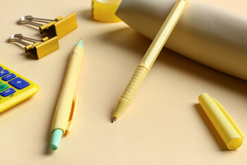 Composition with pencil case, scotch tape, pens, binders and yellow calculator on beige background....