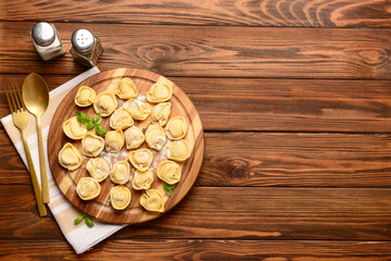 Board with raw dumplings and basil on wooden background