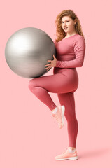 Sporty young woman with fitball on  pink background