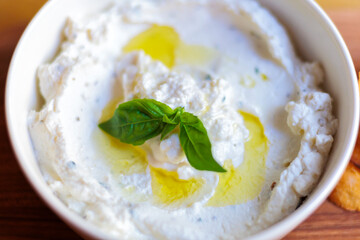 Creamy white dip with basil and olive oil in white bowl